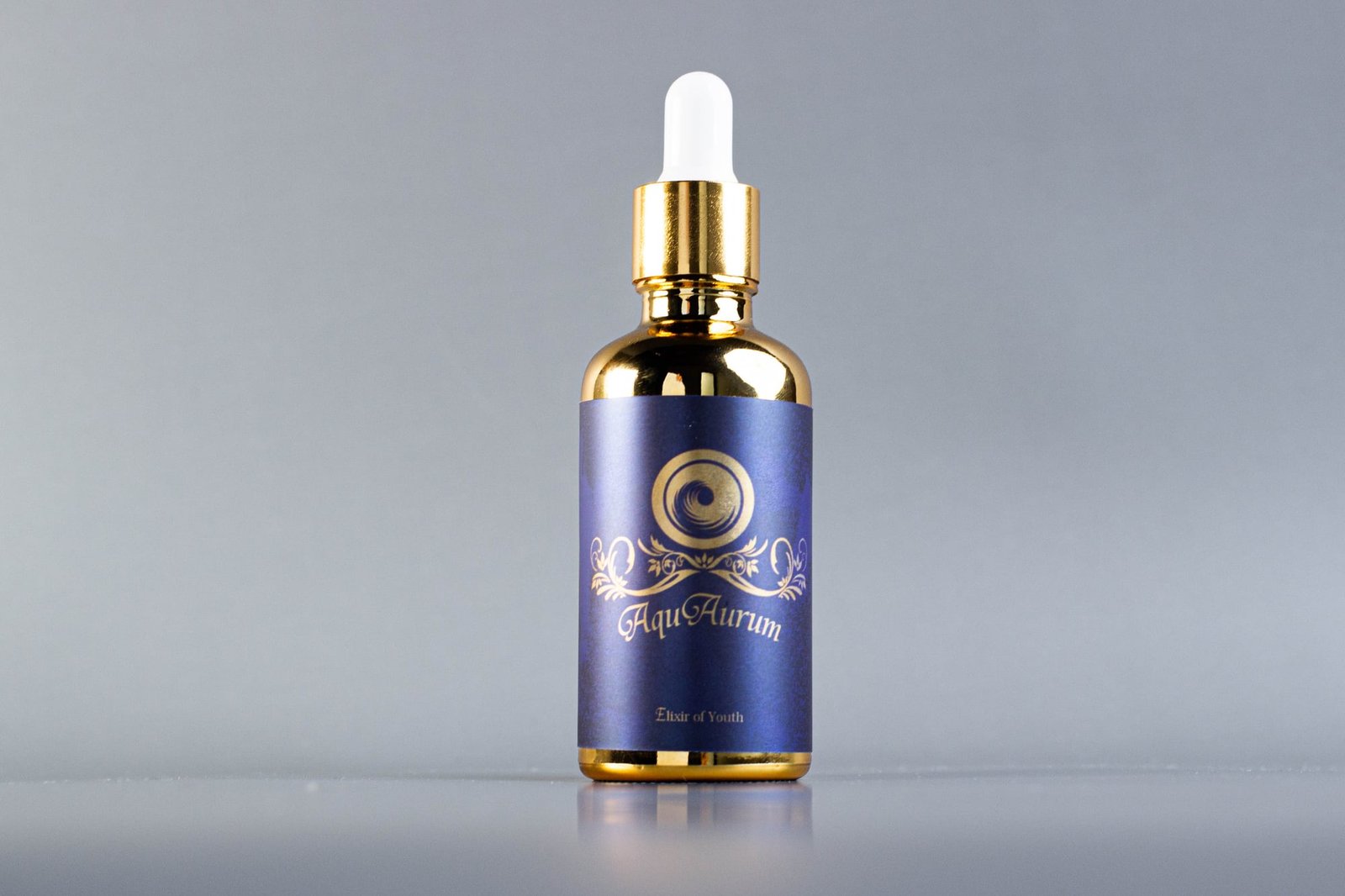 ขวดหยดสีทอง AquAurum พร้อมฉลากสีน้ำเงินเข้ม
