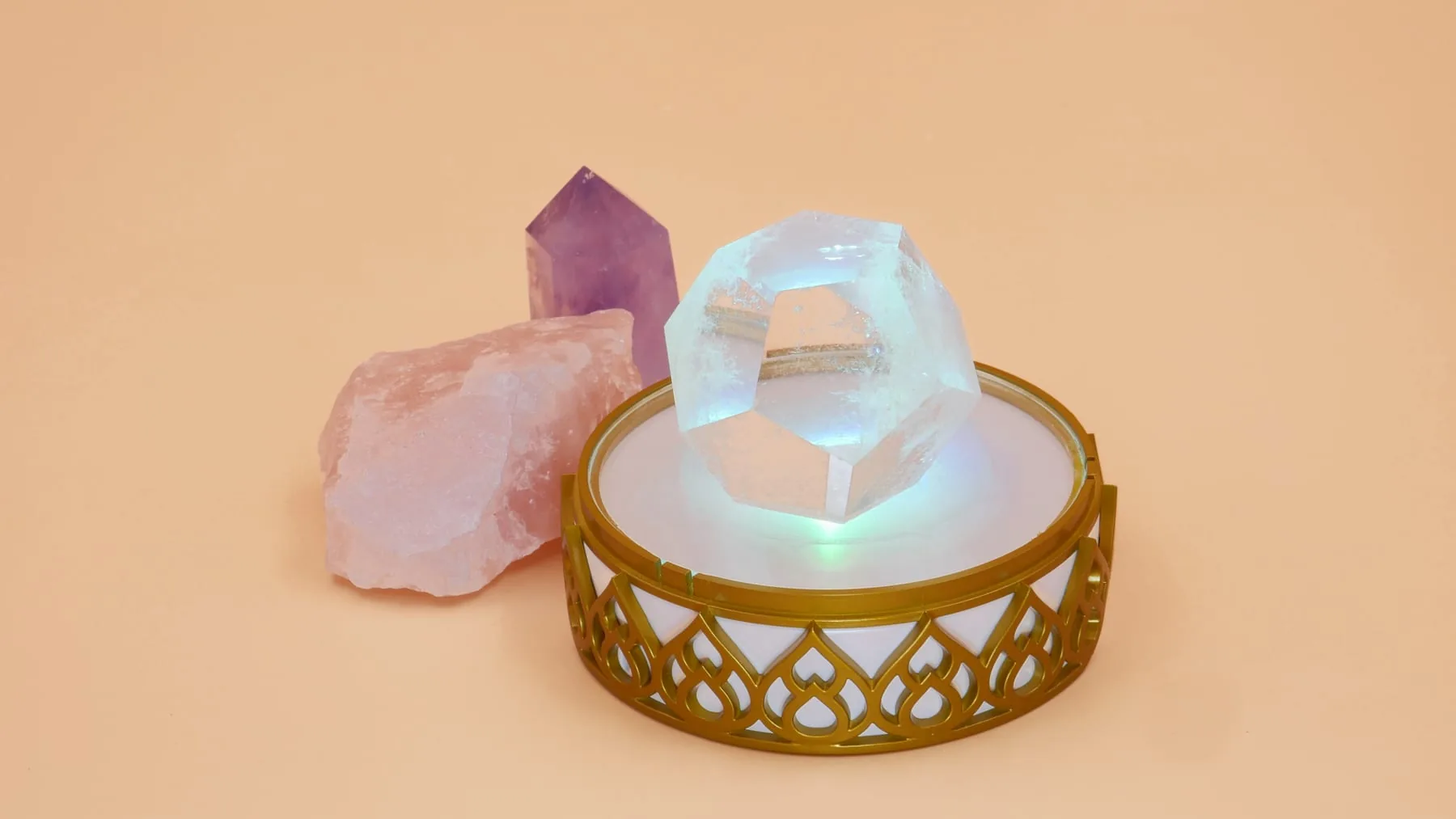 Light Mandalas Chakra Activator glowing beneath clear and rose-colored crystals