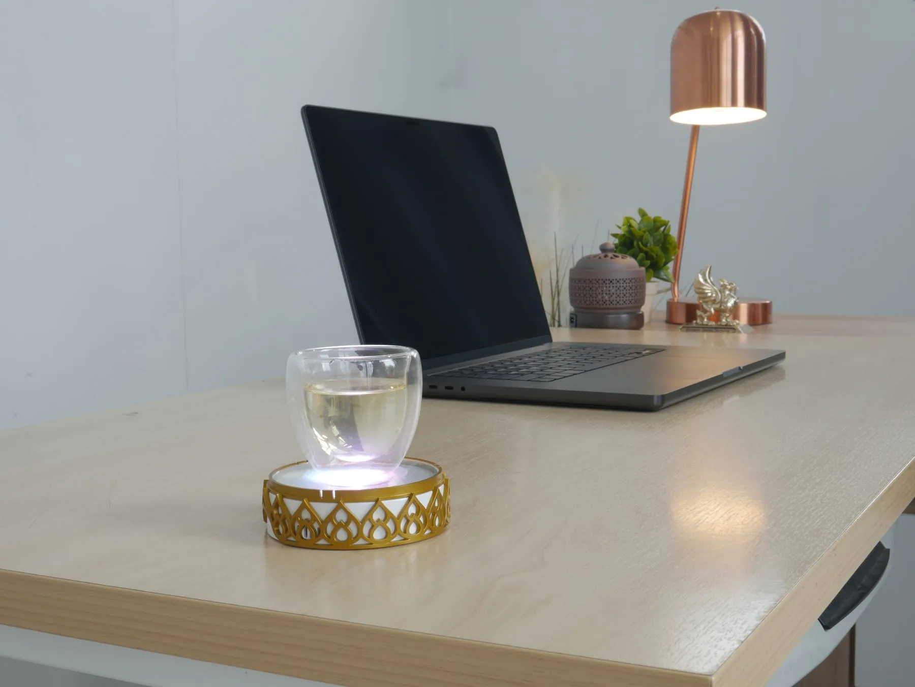 Glass of water illuminated on the Chakra Activator beside a laptop at a work desk