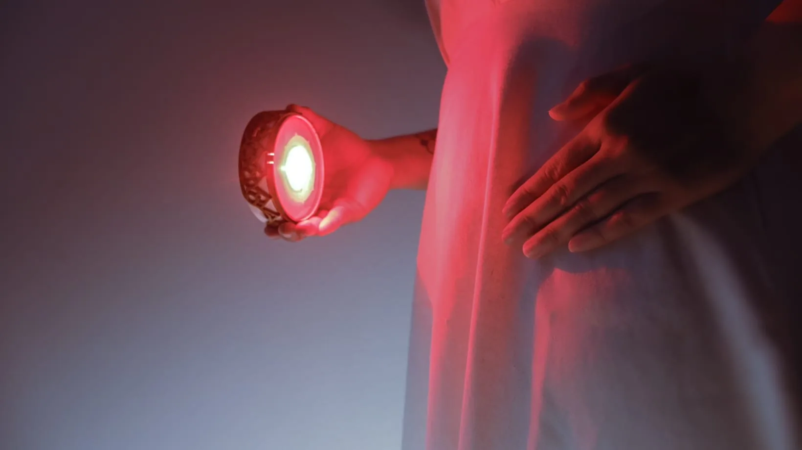 Person holding the red-lit Chakra Activator near the solar plexus area