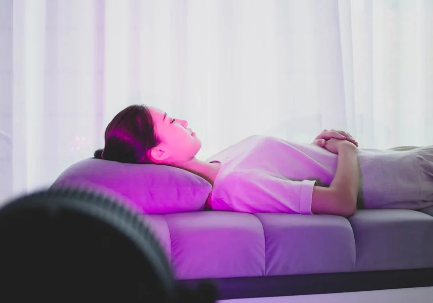 Woman resting comfortably during a soft magenta AuraSync light session