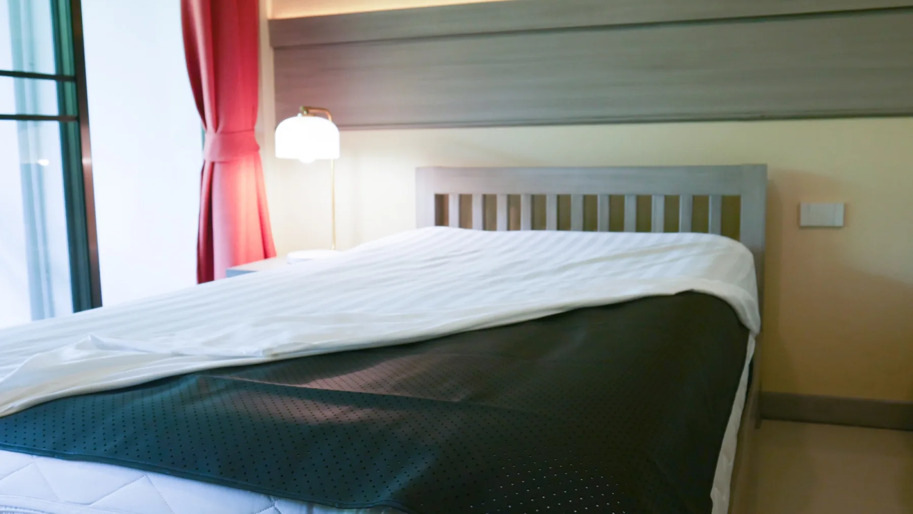 Mandala Earthing conductive mat placed smoothly across a bed beneath a folded white sheet
