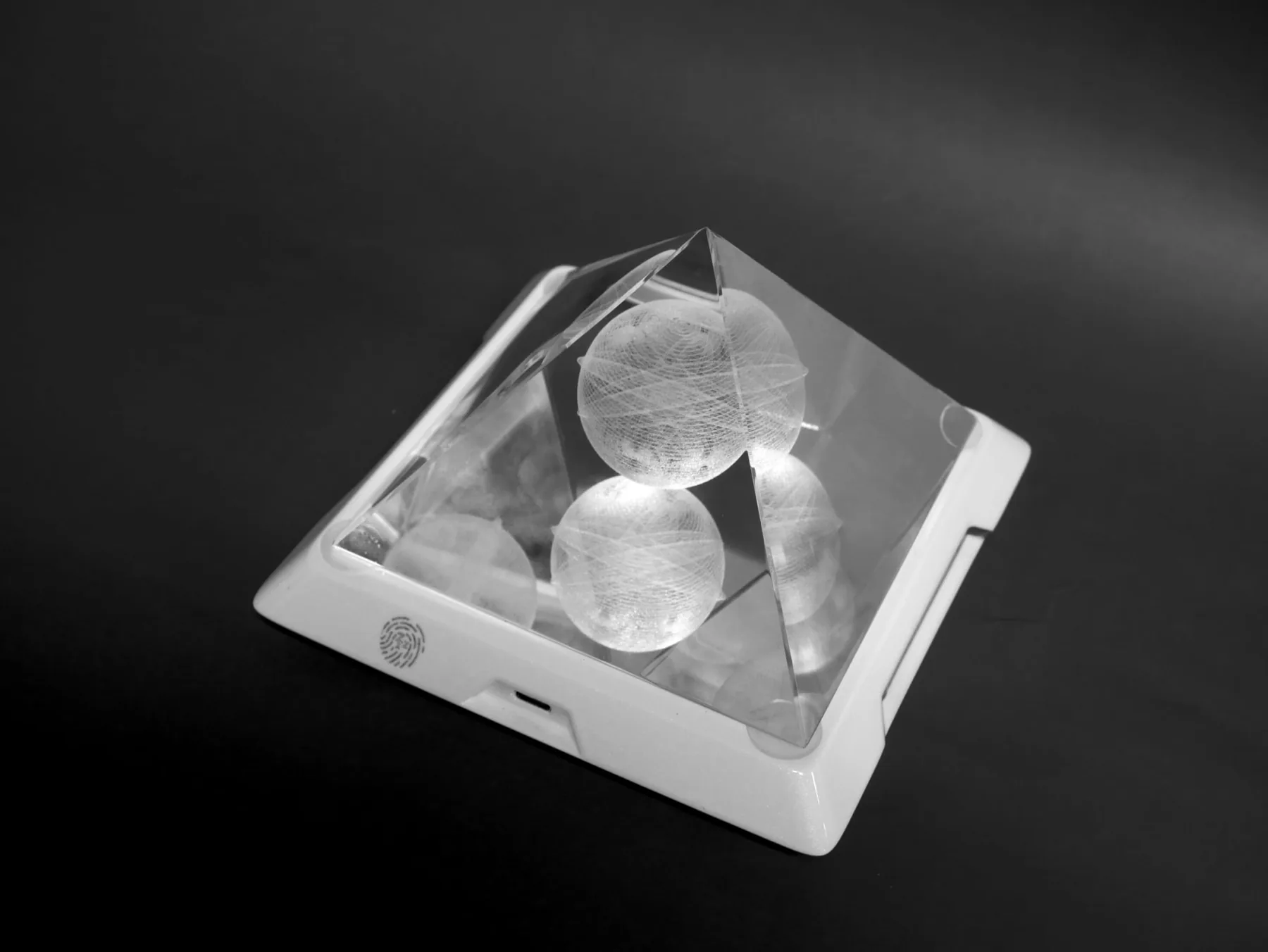 Monochrome close view of the Mandala Resonator pyramid and illuminated engraved crystal spheres