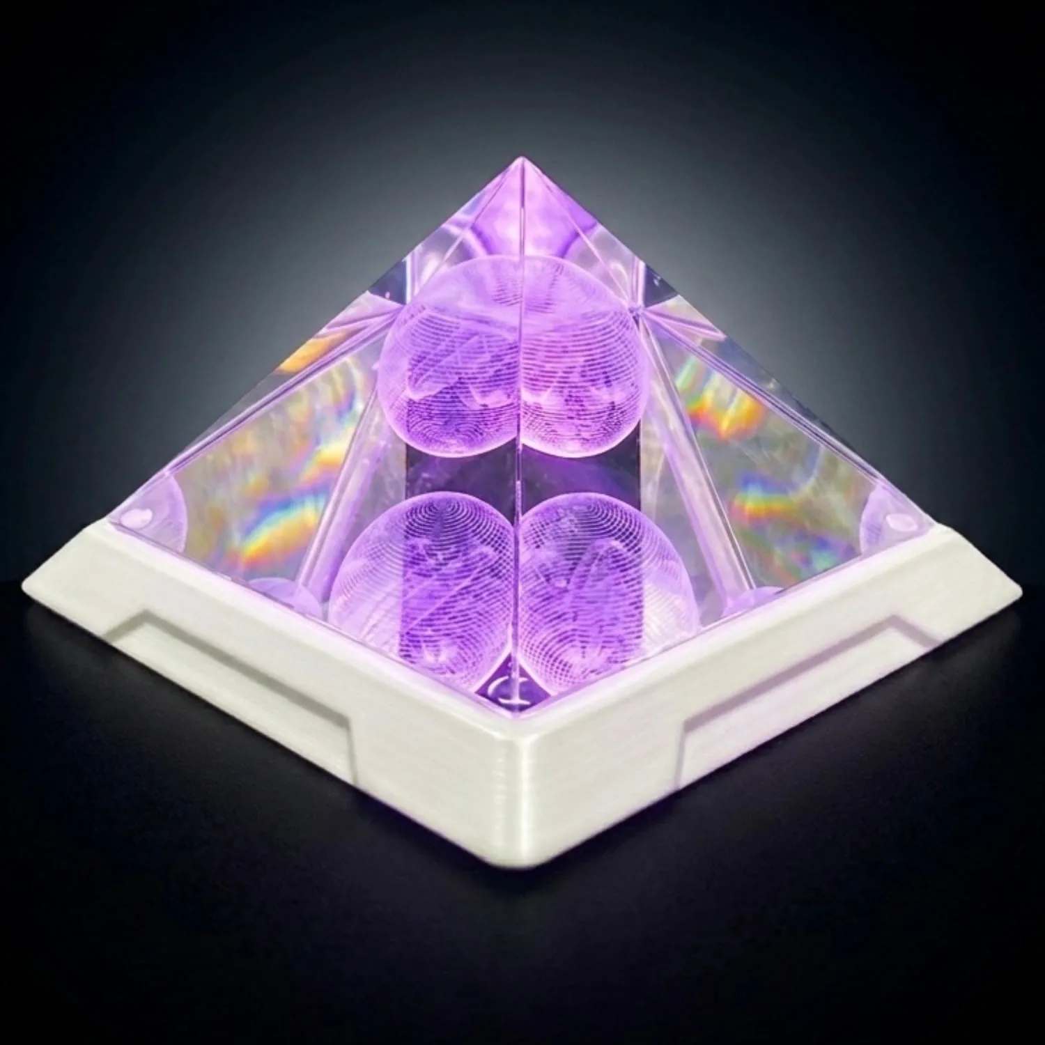 Mandala Resonator transparent pyramid illuminated with violet light against a dark background