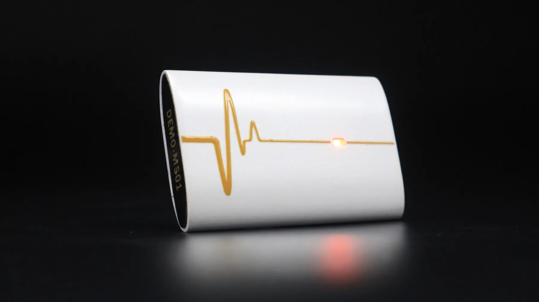 Mandala Scan white coherence device with gold heart-rhythm detail illuminated on a dark studio surface