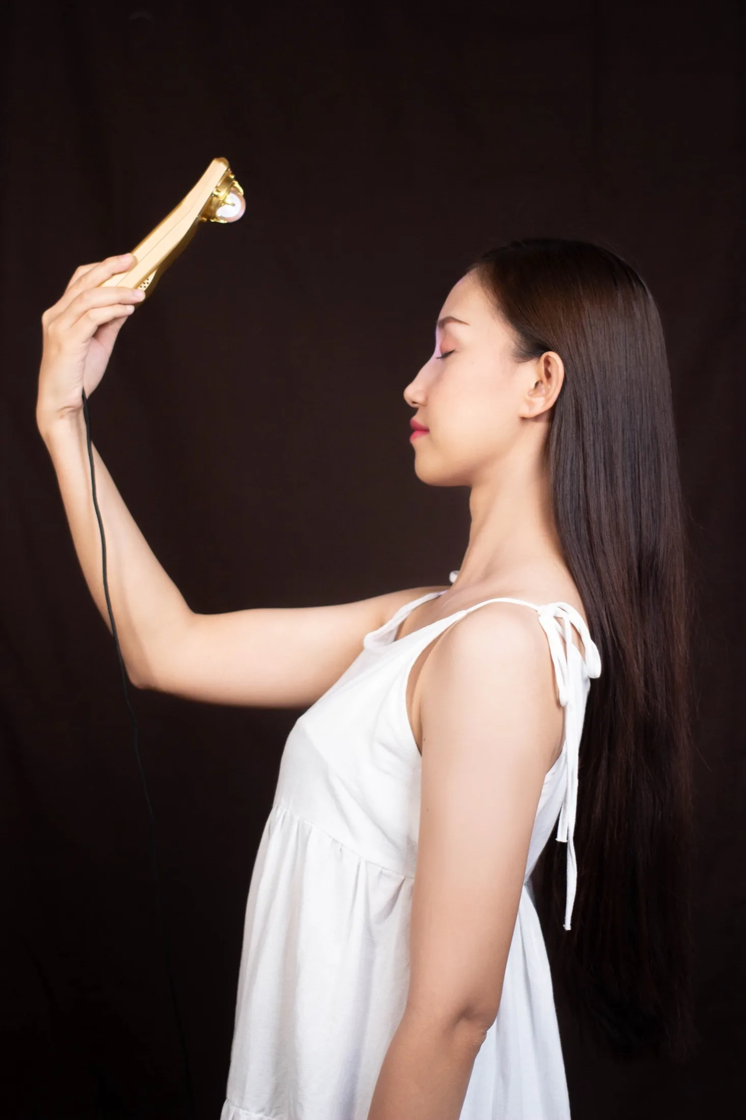 Woman holding the gold Mandala Wand at eye level with her full head and face visible