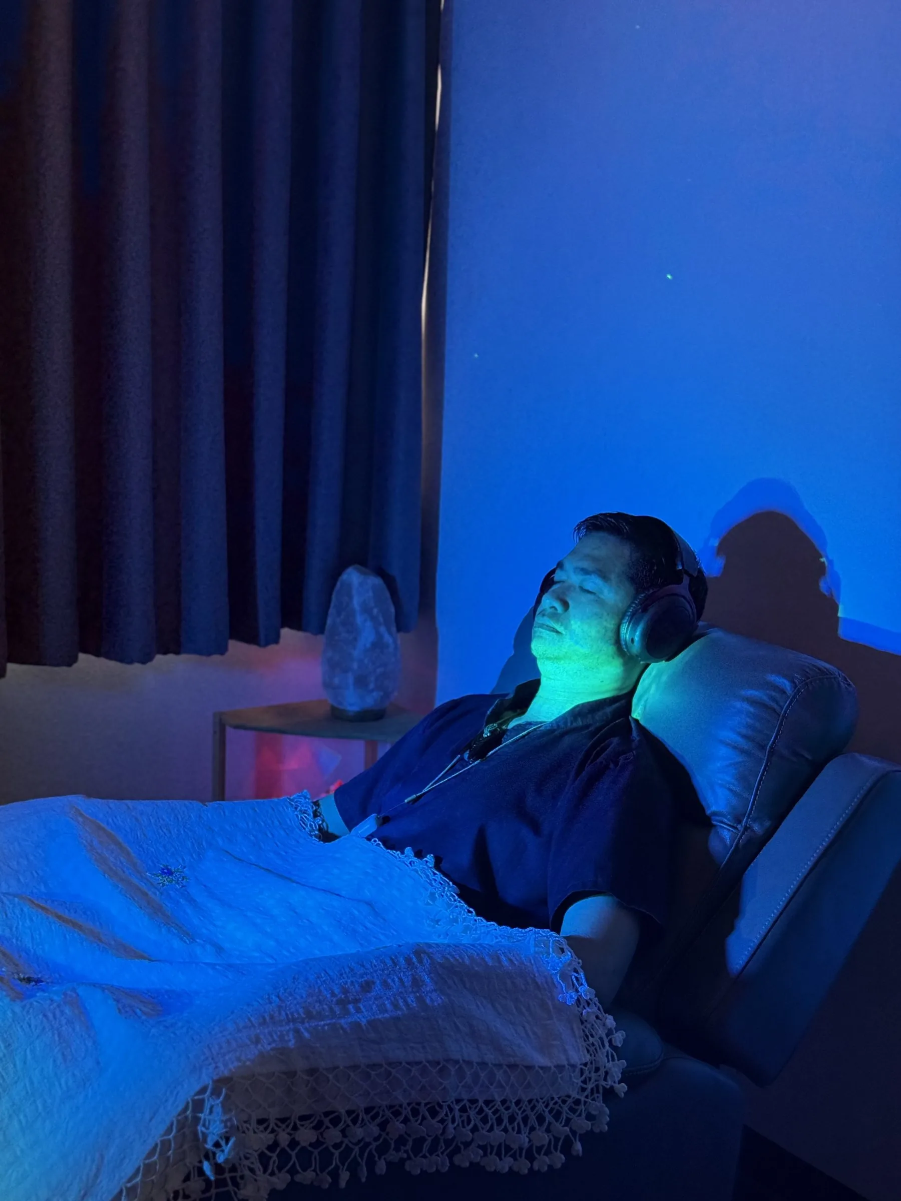 Guest resting with headphones during a warm red and violet Wellness Room session