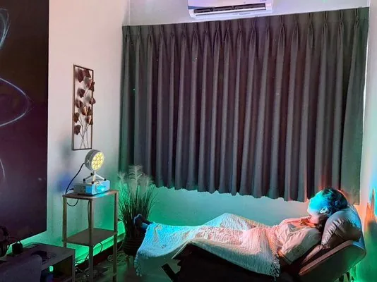 Guest reclining during a Light Alchemy session in a darkened Wellness Room