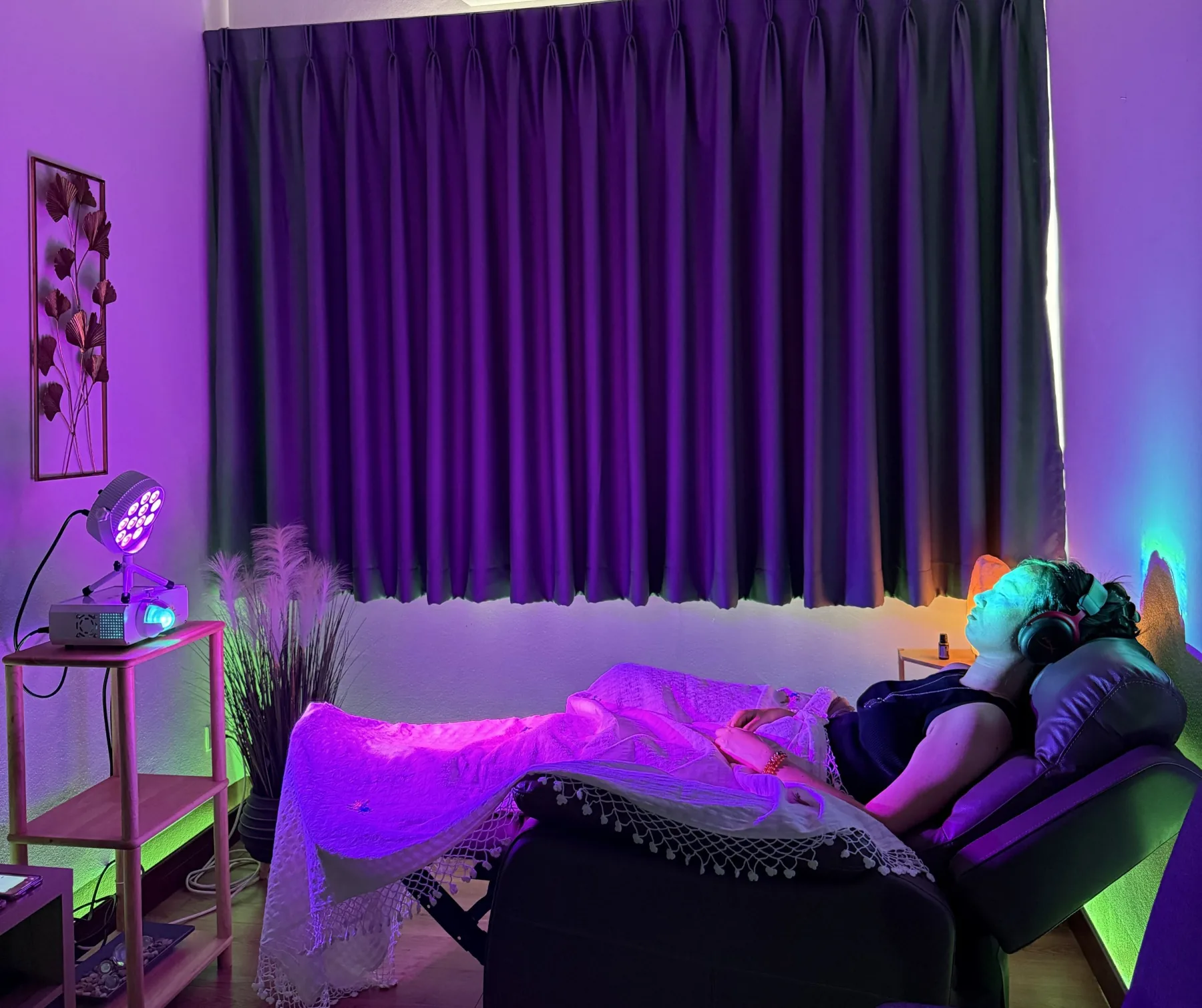 Guest resting under blue, violet, and green light during a Wellness Room experience